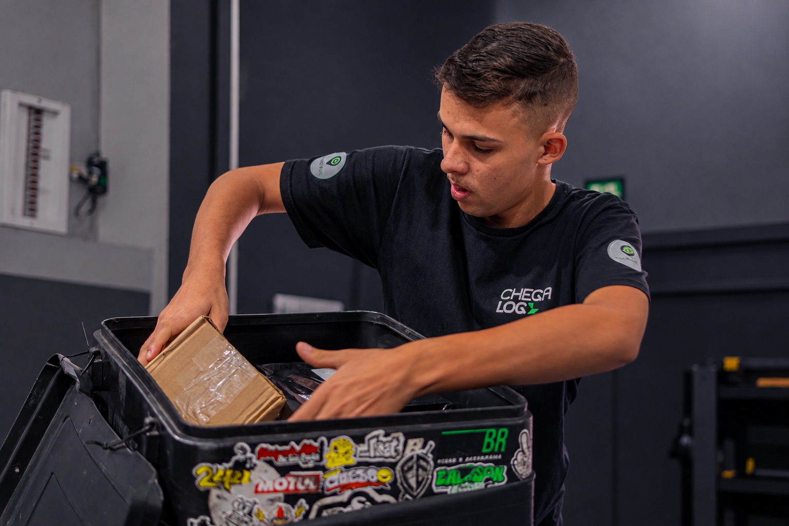 Entregador parceiro da ChegaLog conferindo pacotes ao lado da moto